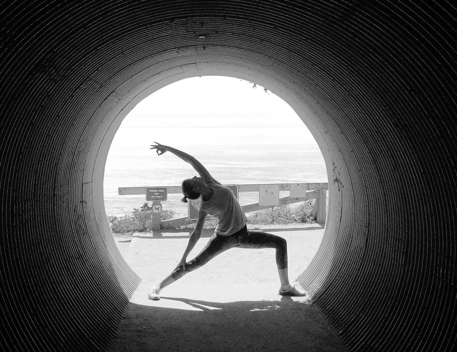 Person practicing yoga pose framed through a circular tunnel